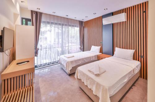 ein Hotelzimmer mit zwei Betten und einem großen Fenster in der Unterkunft Corte Hotel Kaş in Kaş