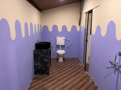 a bathroom with a toilet and a purple wall at Aastha Gokarna in Gokarn