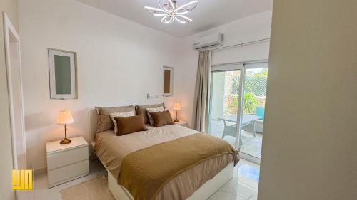 a white bedroom with a bed and a window at 2JA Management Group - Condos White Hill in Sosúa