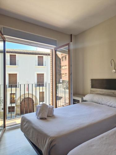 a bedroom with a bed and a large window at Hostal Lizana 2 in Huesca