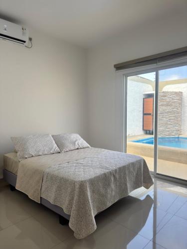 a white bedroom with a bed and a sliding glass door at Casa Privada con Piscina in Salinas