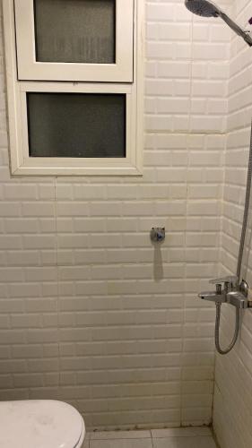 a bathroom with a shower with a toilet and a window at شقة هادئة مودرن in Al Khobar