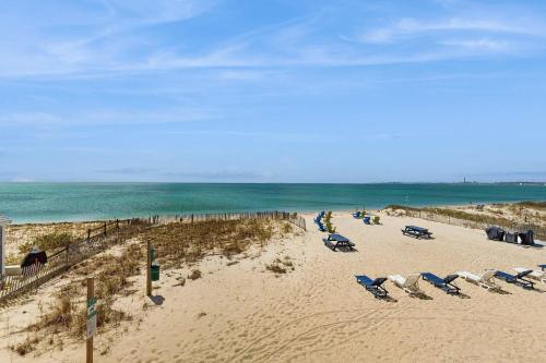 a beach with a bunch of chairs and the ocean at Oceanfront getaway with Bay-view balcony full kitchen AC in North Truro