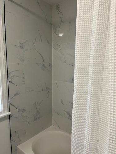 a white bathroom with a shower and a sink at Philly Content House in Marcus Hook