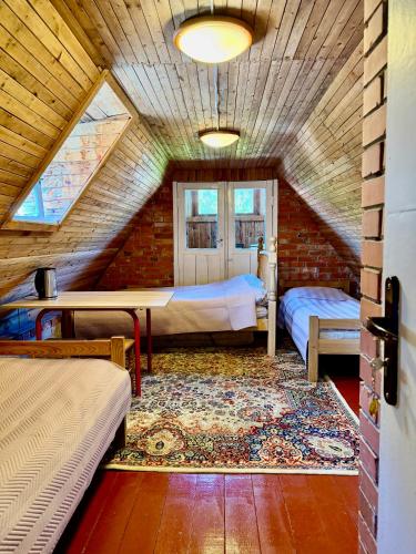 a attic room with two beds and a rug at Skruzdėlynas in Nida