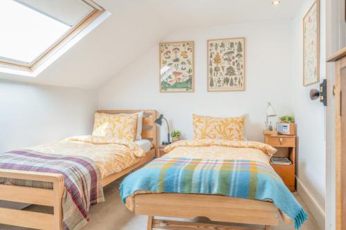 two beds in a room with white walls and a window at North View B&B in Penrith