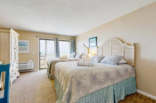 a bedroom with two beds and a large window at Oceanfront hideaway with full kitchen AC sunrise-view balcony in North Truro
