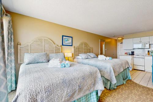 a bedroom with two beds and a kitchen at Oceanfront hideaway with full kitchen AC sunrise-view balcony in North Truro