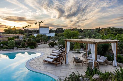 a patio with chairs and a gazebo next to a pool at Masseria Tenuta Specolizzi in Lido Marini