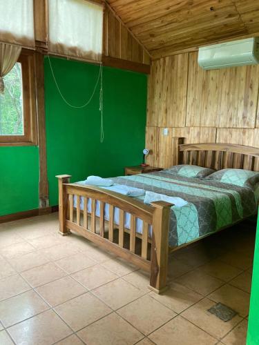 a bedroom with a bed and a green wall at Hostal Flor de Pochote in Masatepe