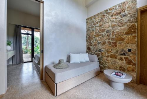 a bedroom with a bed and a stone wall at Karidi Beach Gaia Retreat in Vourvourou