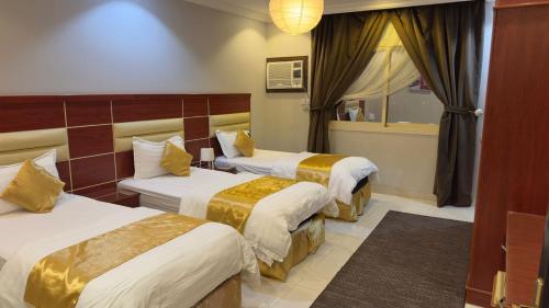 a hotel room with three beds and a window at Zahraa Al-Tal in Baljurashi