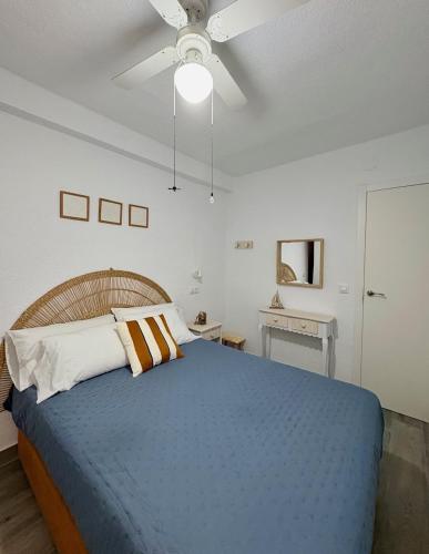 a bedroom with a blue bed with a ceiling fan at Apartamento Galvana in Peniscola