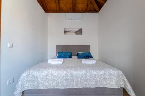 a bedroom with a white bed with blue pillows at Holiday house "Maria" in Privlaka