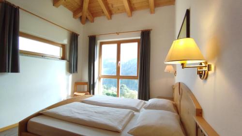 a bedroom with a bed with a large window at Ferienwohnungen Braiter in Rifiano