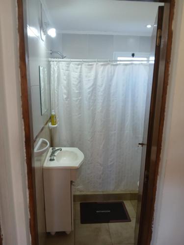 a bathroom with a white shower curtain and a sink at Cabaña Alberto in Balneario Claromecó