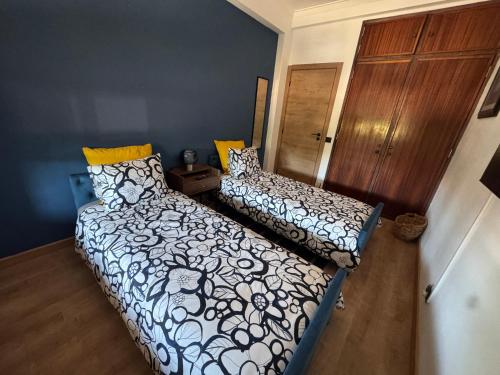 a bedroom with two beds and a wooden door at Margem Rio Residence in Sacavém