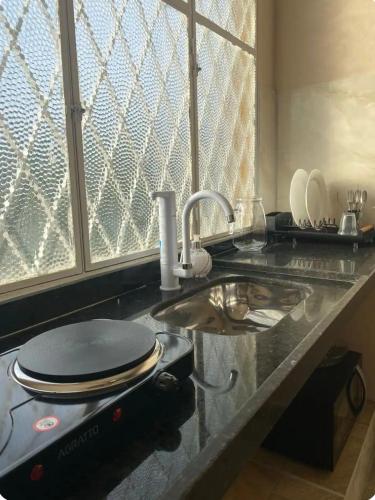 a kitchen counter with a sink and a counter top with a sink at Loft Campinho 1 in Estação Inhoaíba