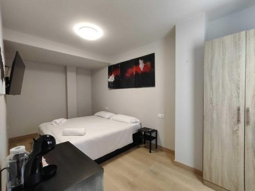 a bedroom with a white bed and a television at Habitación dentro de la Muralla de Lugo 1.3 B in Lugo