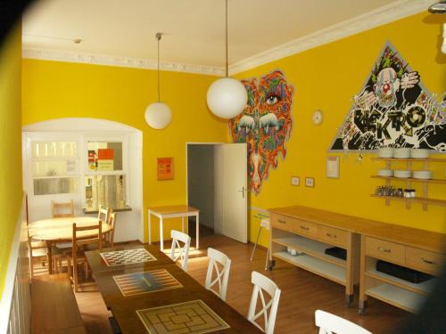 a kitchen and dining room with yellow walls and a table at Happy Go Lucky Hotel + Hostel in Berlin