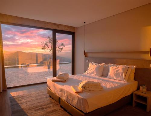 a bedroom with a bed with a large window at Hotel Mezio National Park in Soajo