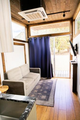 a living room with a couch and a blue curtain at NEW! Modern Cabin Tiny Home at Cliffside #1 in Orderville