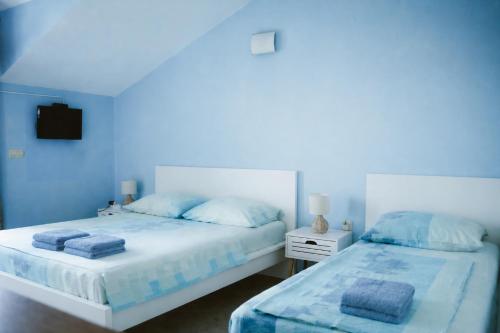 two beds in a blue room with towels on them at Apartmants Bubalo in Trpanj