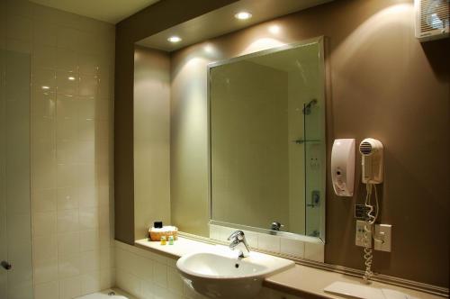 La salle de bains est pourvue d'un lavabo et d'un grand miroir. dans l'établissement Off Broadway Motel, à Auckland