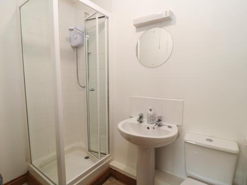 a white bathroom with a sink and a shower at Tithe Barn, Lyneham in Bruern