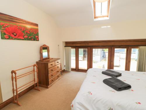 a bedroom with a bed and a dresser and a mirror at Tithe Barn, Lyneham in Bruern