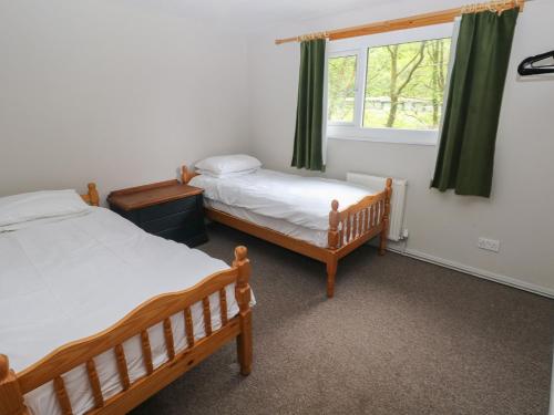 two beds in a room with a window at Cabin No 13 - Salt and Fern Cabins in Port Talbot