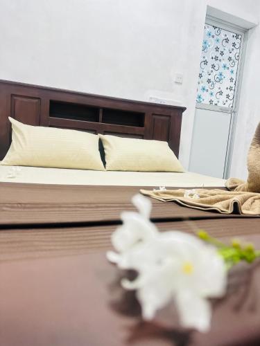 a bedroom with a bed and a table with white flowers at Moonlight Villa in Pottuvil