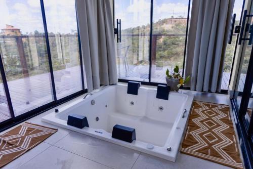 a large white bath tub in a room with windows at Cabanas Mirante do Cerrado1 in Brasília