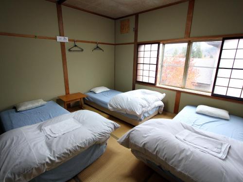 três camas num quarto com três janelas em Towadako Backpackers em Towada