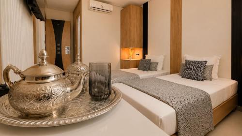 a hotel room with two beds and a tea kettle on a table at Hotel Vents Des Iles in Essaouira