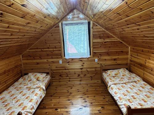 two beds in a wooden room with a window at Ivanovo Polje Chalet in Pljevlja