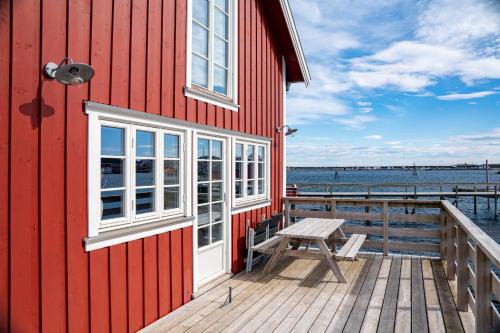 a red building with a picnic table on a dock at Reine seaview cabin in Reine