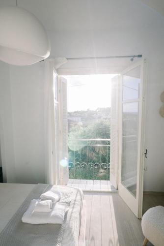 a white bedroom with a bed and a large window at Benjamin Luxury Suite by The Eustas in Pylos