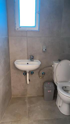 a bathroom with a sink and a toilet and a window at Charming Village Farmhouse, Çukë in Sarandë