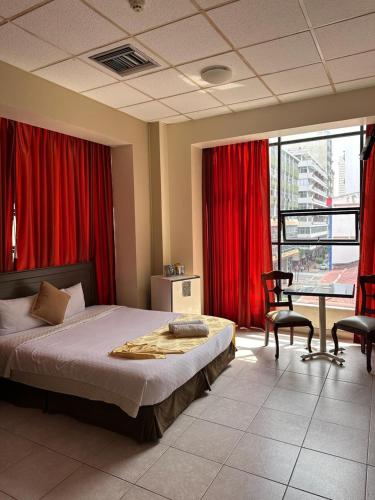 a bedroom with a large bed and red curtains at Hotel Las Peñas in Guayaquil