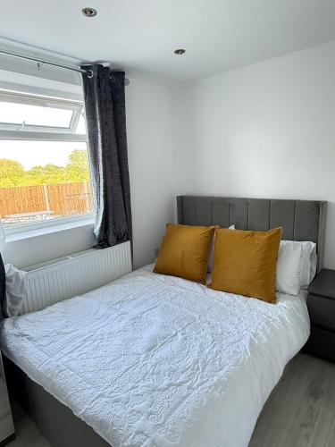 a bedroom with a bed with yellow pillows and a window at One Bedroom Luxurious Flat - Free Parking in Rochester