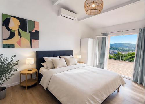 a white bedroom with a bed and a large window at Villa Bellevue, magnifique vue mer! Piscine chauffée, à10 mns de la plage et du centre! in Cavalaire-sur-Mer