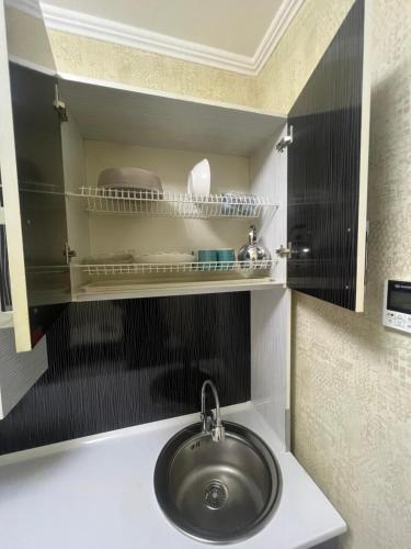 a sink in a bathroom with a shelf above it at Уют как дома in Shymkent