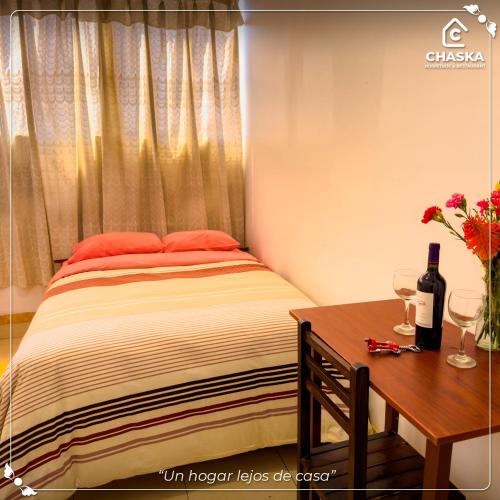 a bedroom with a bed and a table with wine glasses at Chaska Backpackers & Rooms in Ayacucho