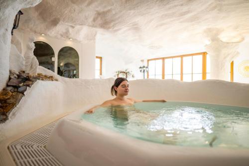 a woman in a hot tub in a white room at Glocknerhaus in Berg im Drautal