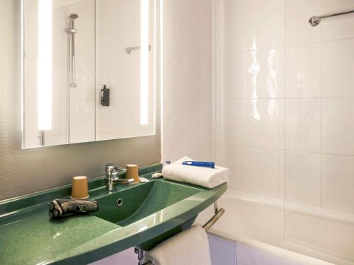 a bathroom with a green sink and a shower at ibis Arles in Arles