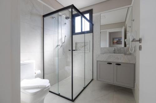 a bathroom with a glass shower and a toilet at 1986 Apparts in Águas de São Pedro
