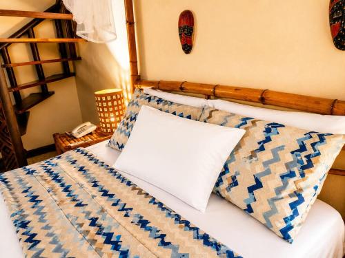 a bed with a wooden headboard and pillows on it at Hotel Punta Teonoste Boutique Beachfront Resort in Popoyo