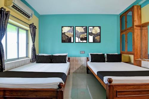 two beds in a room with blue walls at Hotel O Green House in Lālbāgh