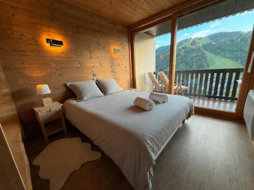 a bedroom with a large bed and a large window at Morz'Inn Vue panoramique sur les montagnes in Morzine